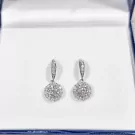 1-carat round moissanite diamond halo drop earrings in a jewelry box.