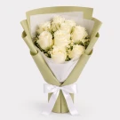 White roses and chamomile flowers in olive green wrap with a white bow.