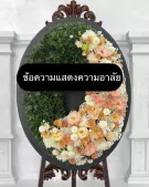 Funeral wreath with green foliage and pastel flowers, bearing the text "ข้อความแสดงความอาลัย".