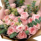 Bouquet of 24 pink roses with eucalyptus leaves, wrapped in brown paper.