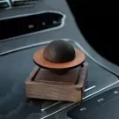 Planet-shaped wooden oil diffuser on a car console.