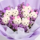 A bouquet of white fluffy sheep with colorful felt ears nestled amongst purple and pink dried flowers.