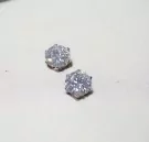 Two sparkling 1-carat round-cut moissanite diamond stud earrings on a white surface.