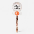 A 24" clear glitter balloon with "Happy Birthday GATTUI" written on it, with smaller white and orange balloons below and rose gold tassels.