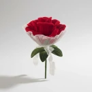 Giant red velvet rose with white tulle and green leaves tied with ribbon.