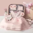 Pastel pink baby gift set in a suitcase with a princess dress, shoes, gloves, and accessories.