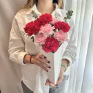 Woman holding a vase of red and pink carnations, "FLOWERS BLOOM FOR YOU" text visible on the vase.