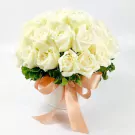 White roses in a round box tied with a peach ribbon, on a white background.