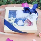 Thai Water Ceremony Set M gift box with white fluffy items, white flower garland, small white candies, and a perfume bottle.