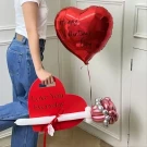 A heart-shaped Valentine's balloon bouquet held by a person.