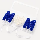 Blue and white roses spelling "MOM" in a white box with a ribbon.