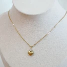 Gold chain necklace with a heart pendant accented by a small crystal.