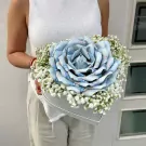 A heart-shaped box filled with baby's breath and a large rose made of blue banknotes.