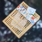 A woven bamboo box filled with Khao Chae ingredients and topped with a floral ribbon and label.