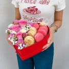Heart-shaped box with pink roses, purple daisies, white baby's breath, and pink and vanilla macarons.