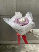 Bouquet of pink limonium with a single white rose, wrapped in white paper and tied with a red ribbon.