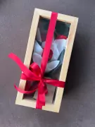 Wooden box with three preserved red and white roses, tied with a red ribbon.