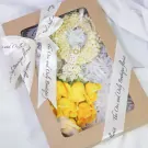 Brown box with white ribbon, white flower garland, and yellow roses inside.