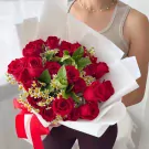 A large bouquet of 24 red roses with white accents and green leaves, tied with a red ribbon.