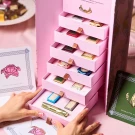 Pink tiered chocolate box with assorted individually wrapped chocolates and a rose card.