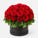 Round black box filled with 40 vibrant red roses and greenery.