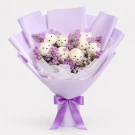 A bouquet of white teddy bear-shaped flower arrangements with purple and pink ears, wrapped in lavender paper and tied with a purple ribbon.