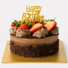 Chocolate cake with strawberries, chocolate ganache, and chocolate shavings, topped with a "Happy Birthday" sign.