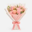 Pink and peach floral bouquet with roses, carnations, and tulips, wrapped in white paper with a pink ribbon.