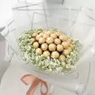 Bouquet of 19 gold-wrapped Ferrero Rocher chocolates surrounded by white baby's breath flowers and sheer white wrapping.