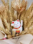 Maneki-Neko cat with gold accents and wheat stalks in a pink hatbox.
