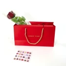 Red gift bag with a rose and a sticker showing 18 chocolates.