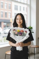 Woman holding a bouquet with small crocheted figures wearing graduation caps.