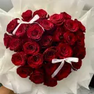 Heart-shaped bouquet of 30 vibrant red roses with white ribbon accents.