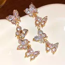Dangle earrings with gold-tone metal, featuring multiple clear, sparkling zircon-encrusted butterfly charms.