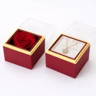 Two red jewelry boxes with gold trim, one holding a red rose, the other a diamond necklace.