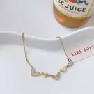 Gold necklace with five alternating white and gold heart charms on a white cloth background.