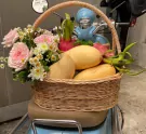 Fruit basket with mangoes, dragon fruits, and pink roses on a blue scooter.