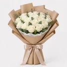 A bouquet of 30 pristine white roses with eucalyptus, wrapped in light brown paper and tied with a ribbon.