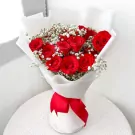 Bouquet of 15 deep red roses with baby's breath, wrapped in white paper and tied with a red ribbon.