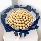 A large bouquet of 100 Ferrero Rocher chocolates, wrapped in dark blue paper with white ribbons.