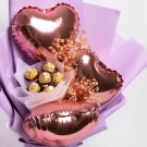 Three pink heart-shaped balloons and five Ferrero Rocher chocolates in a bouquet.