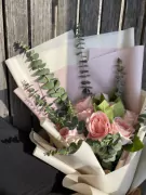 Pink roses and eucalyptus bouquet wrapped in cream and pink paper.