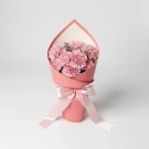 Pink carnations wrapped in coral paper with a light pink ribbon bow.