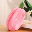 Plush strawberry toy with a zipper, featuring green leaves and yellow seeds, on a wooden surface.