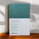 Back cover of "Before the Coffee Gets Cold" book with text and teal patterned top.