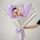 Graduation teddy bear bouquet with dried flowers and purple wrapping.