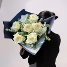 White roses with baby's breath and eucalyptus in navy blue wrapping paper.