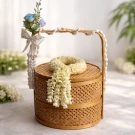 A woven bamboo basket with a jasmine garland and pearl strands.
