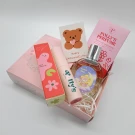 Gift set with perfume bottles, a cute bear card, and a pink box.