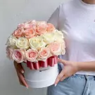 Round white box with 40 white and pink roses, adorned with a pink ribbon, held by a person in a white t-shirt and jeans.